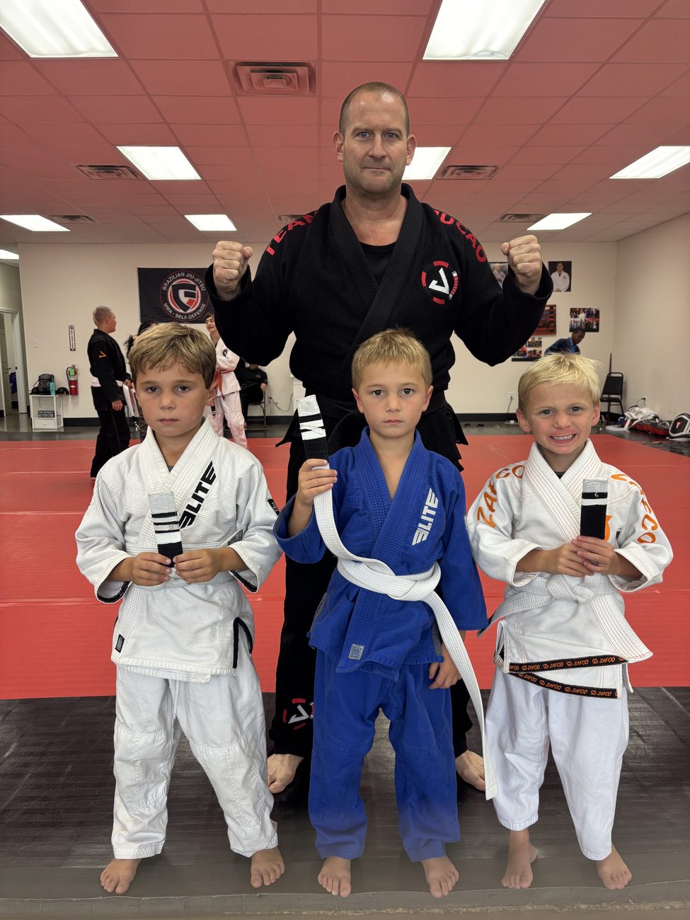 Coach Simoneaux in his jiu-jitsu black belt with his sons